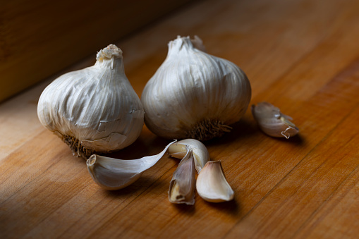 Garlic cloves on a wooden cutting board.