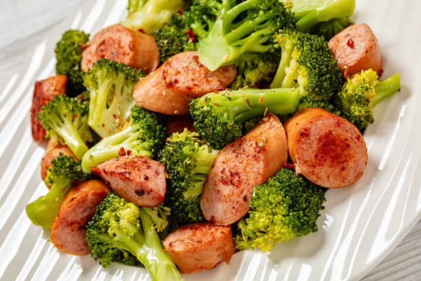 pan seared juicy sausage and crispy tender broccoli on white plate, close-up