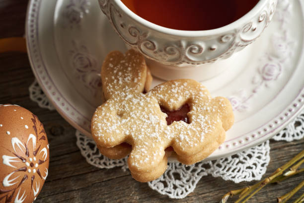 istock Bunny shaped homemade Linzer cookie with a cup of tea and an Easter egg decorated with wax 2150198618