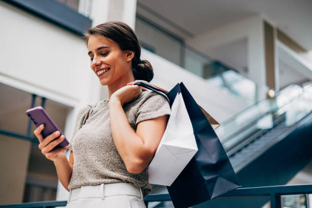 Happy Woman Shopping and Using Smartphone in Modern Mall