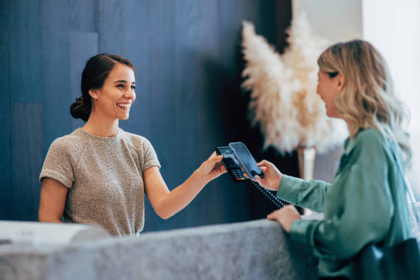 istock Smiling Receptionist Taking Payment at Modern Hotel Desk 2150200175
