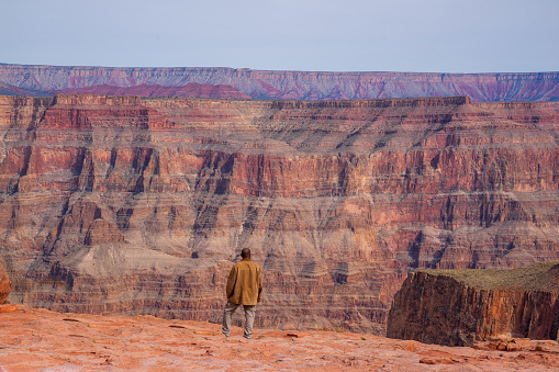A man enjoys the spectacular view of red mountains at Grand Canyon West. One of the world heritage, a worldwide geological phenomenon known as the Great Unconformity of rock in which 250 million-year-old rock strata lie back-to-back with 1.2 billion-year-old rocks.