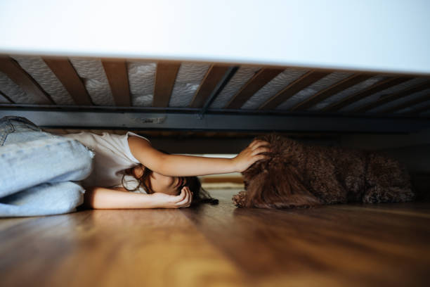 istock Little gilr hiding under a bed 2150202781