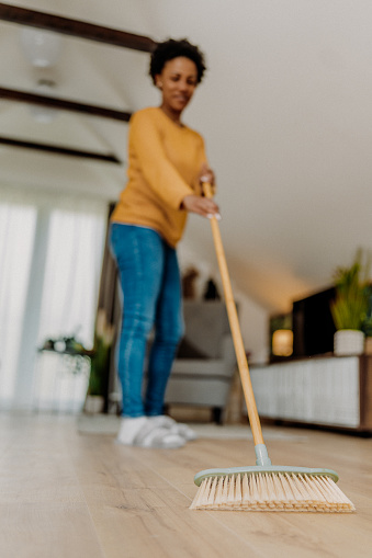Mid adult woman using her broom in the bedroom
