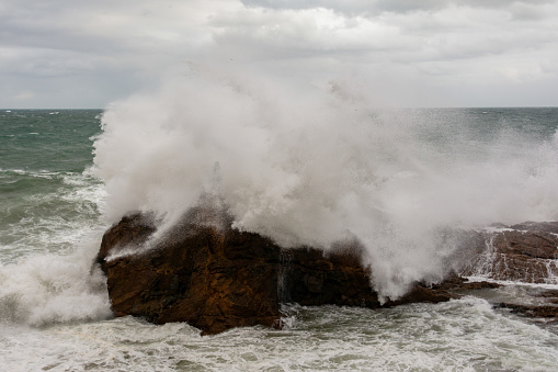 Waves hitting a sea rock with great force. winter storm.