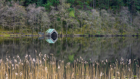 Boathouse reflected in the waters of Loch Ard near Aberfoyle, Scotland.