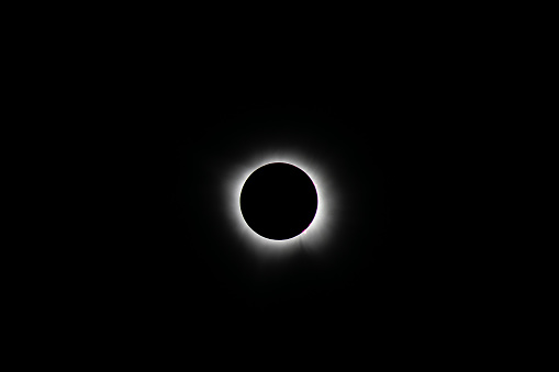 Total solar eclipse during totality near Mount Ida, Arkansas on April 8, 2024.  Solar prominences can be seen at the edge of the black moon with the corona emanating out