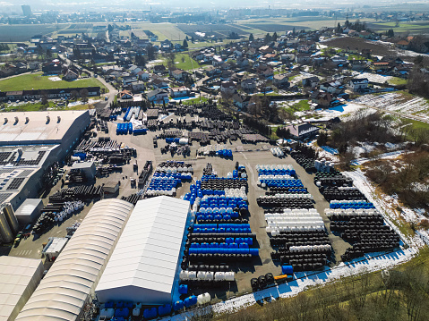 Aerial shot of blue and white septic tanks stored outside the factory on the ground. Large production facility of plumbing supplies on the outskirts of the city.