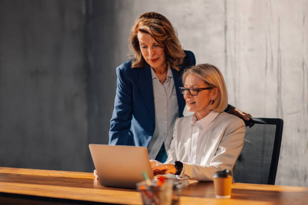 istock Senior executive typing on a laptop at office and her colleague watching 2150214725