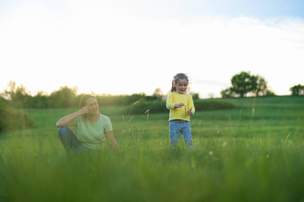 Nature Lovers. Mom and Daughter Play in Green Meadow on a Spring Day. Teach Gen Alpha Kids to Love Nature.