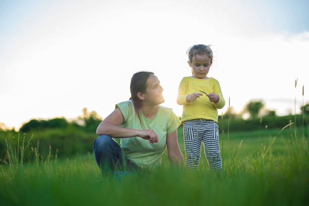 Nature Lovers. Mom and Daughter Play in Green Meadow on a Spring Day. Teach Gen Alpha Kids to Love Nature.