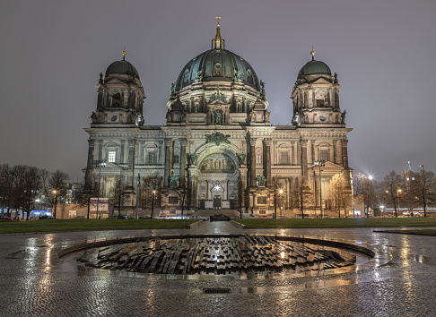 Berlin, Germany - Dec 19, 2023 - Picturesque view of The berlin cathedral building with Modemer Brunnen fountain on the foreground at dusk. Berlin Cathedral Berliner Dom in Berlin, Space for text, Selective focus.