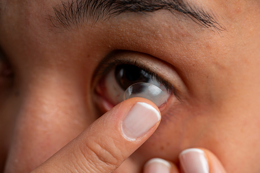 woman placing contact lens on her eye
