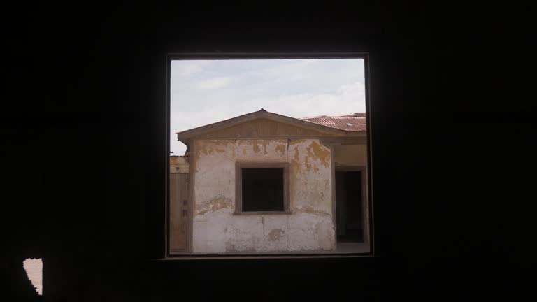 Abandoned Humberstone saltpeter factory in Chile, viewed through a derelict window frame