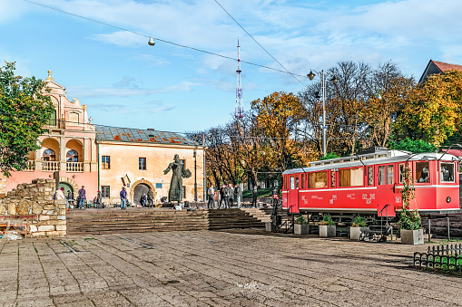 Lviv, Ukraine - November 2, 2023: Pink-red tram car near the Ivan Fedorov Statue at the Second hand book market in Lviv on an autumn morning. Autumn cityscape in famous tourist place