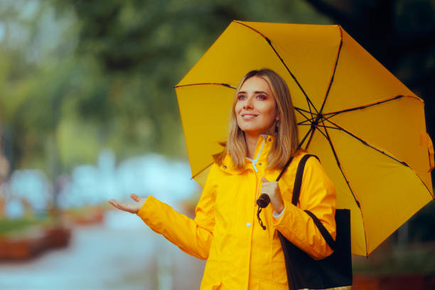 istock Woman With Yellow Jacket and Umbrella Checking Rain 2150224837