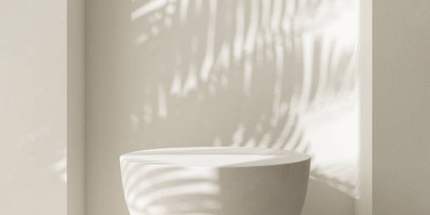 istock Cream white round podium table in sunlight, palm tree leaf shadow on wall 2150225947