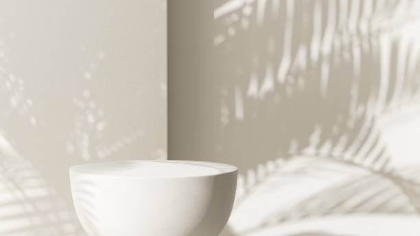 istock Cream white round podium table in sunlight, palm tree leaf shadow on wall 2150225955