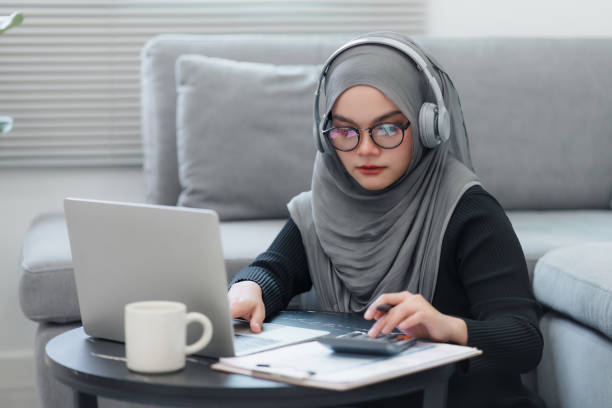 istock A Muslim woman focused on her work, using a laptop and taking notes, while sitting at her home workspace. 2150226429