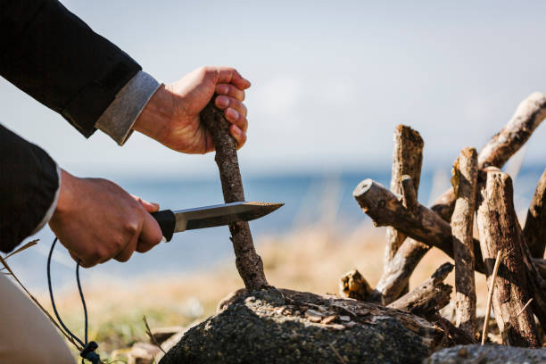 Asina man cutting wood branch with knife.