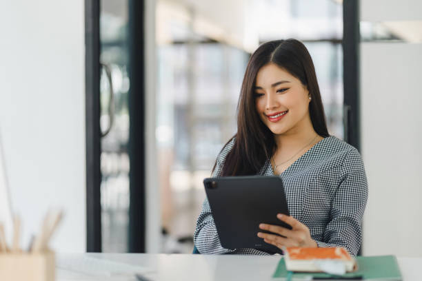 istock Asian professional businesswoman working on tablet computer in a corporate office. 2150227162