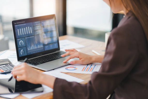 istock Business professional working on laptop with analytics dashboard, surrounded by financial reports. 2150230437