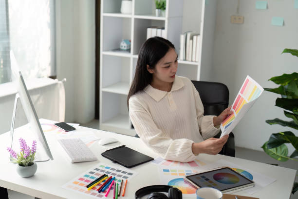 istock Asian woman freelance graphic designer working with color swatch samples and computer at desk in home office, young lady choosing color gamma for new design project 2150234629