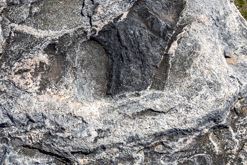 This image shows a full frame abstract texture background of the textured surface on a large striated granite rock.