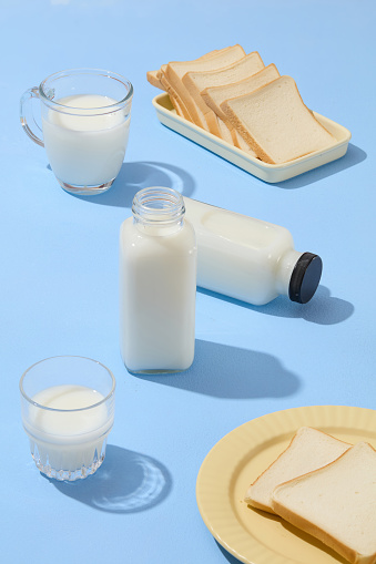 On the blue surface, two ceramic dishes featured some sandwich slices arranged with cups and unbranded bottles of milk. Blank label for beverage brand promotion