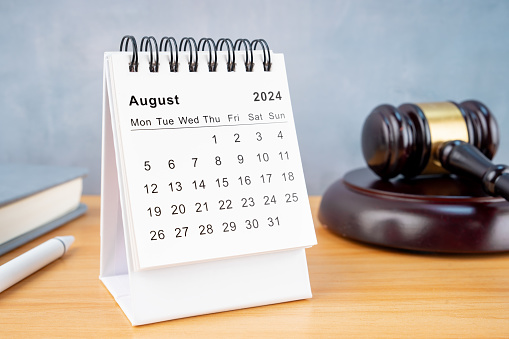 Desk calendar for August 2024 and judge's gavel on the worktable.