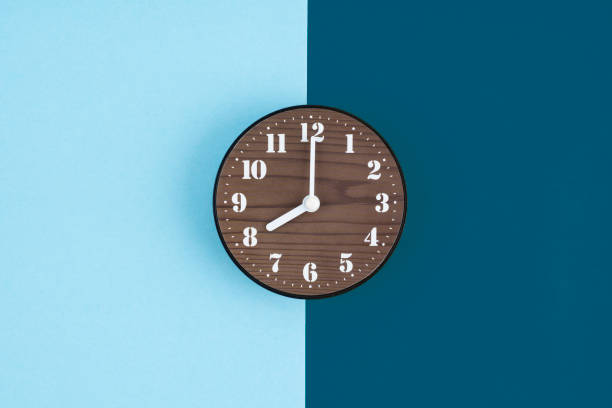 istock Wooden clock placed in middle of blue background. 2150238848