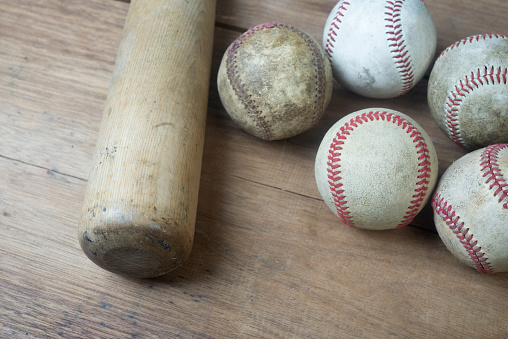 Close up old baseball and wooden bat on a wooden table. select focus.