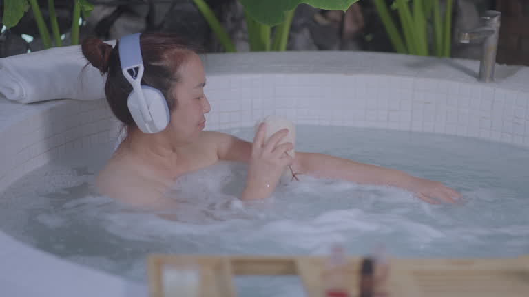 Asian Woman Enjoying Music in a Relaxing Bath, Handheld Shot