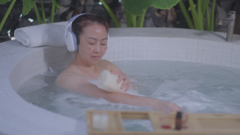 Asian Woman Enjoying Music in a Relaxing Bath, Handheld slow-motion capture