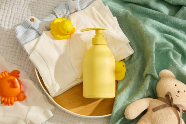 istock Many baby accessories neatly arranged on table with blank label yellow bottle contained on wooden tray in center for advertise shampoo or shower gel for baby . Above view photo, copy space 2150247140