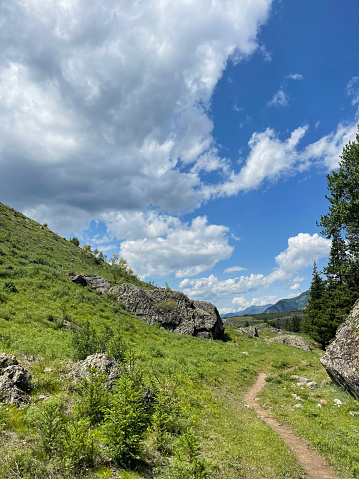 Mountain landscape with rocks and grass under blue sky with white clouds