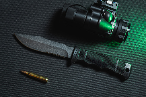 Tactical knife with a fixed blade, gt14 night vision device and 5.56x45mm cartridge. Close up photo