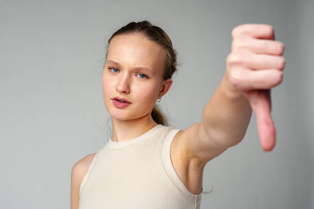 istock Young Woman Giving Thumbs Down Gesture Against a Neutral Background. 2150249909