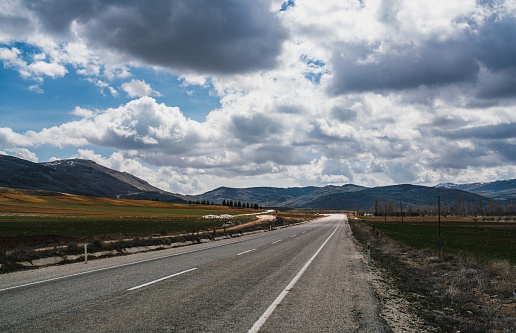 Asphalt road in fields and mountains on background