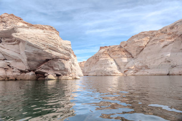 Antelope Canyon from Lake Powell captures the mesmerizing beauty where water meets stone. Towering sandstone cliffs frame the tranquil waters of Lake Powell, leading the eye towards the iconic slot canyons of Antelope Canyon. The play of light and shadow creates a breathtaking scene, showcasing nature's masterpiece of erosion and geological wonder