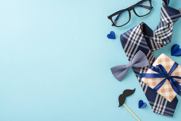 istock Show appreciation for Dad on Father's Day with tasteful top view arrangement comprising elegant necktie, bow tie, giftbox, glasses, mustache on tranquil blue background, perfect for your promotions 2150252269