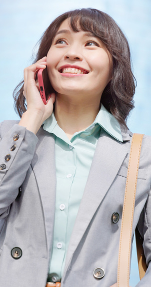 closeup asian businesswoman talk on smartphone happily outdoor downtown