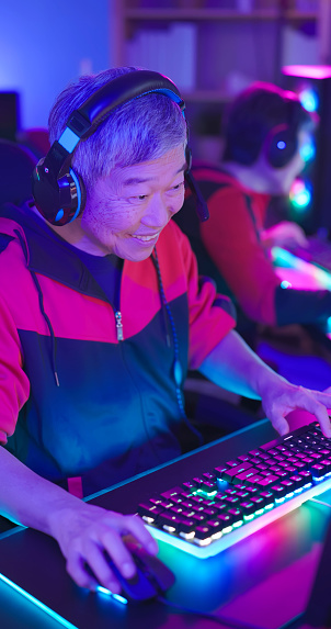 closeup asian elderly male gamer wear headset play online internet cyber sport game at home - he feel frustrated after losing