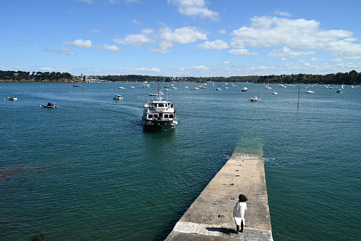 Dinard, France, april 18, 2024 : Corsaire shipping company boat between Saint-Malo and Dinard arriving at the disembarkation quay with a woman from behind waiting