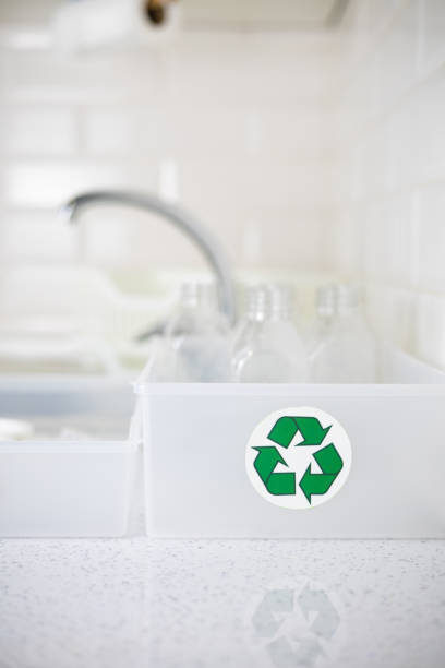 istock Vertical. A box with a recycling sign and plastic bottles inside stands on a kitchen table. Sorting plastic in the kitchen at home to be sent for recycling. The concept of recycling plastic. 2150257450