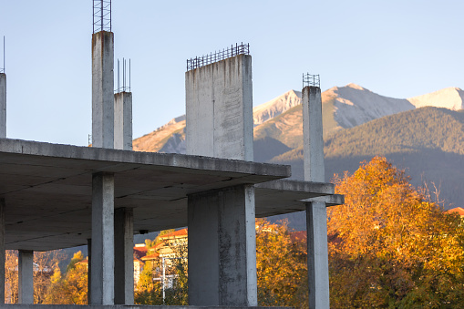 Abandoned construction, unfinished frame reinforced concrete building in Bansko, Bulgaria, Pirin mountains behind