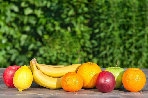 Fruits on wooden table on nature background.
