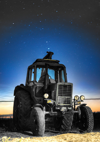 An old tractor on the background of the starry sky