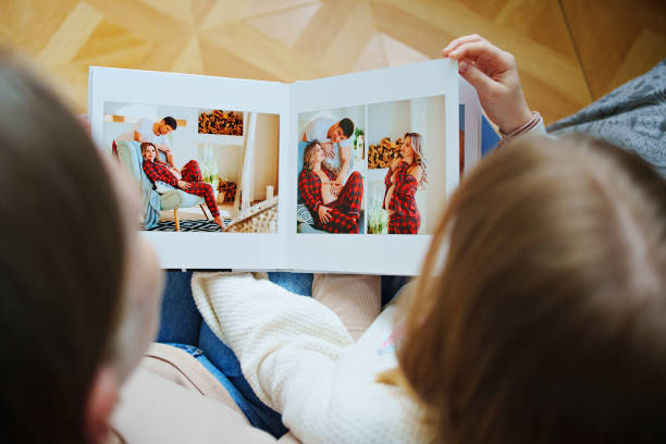 mother and daughter flips through a book with photos of dad and pregnant mom. mother and daughter flips through a photo book with photos of dad and pregnant mom. Beautiful memory. Professional photo printing. services of photographer and designer. original gift for the family. cute pregnant woman with gift stock pictures, royalty-free photos & images