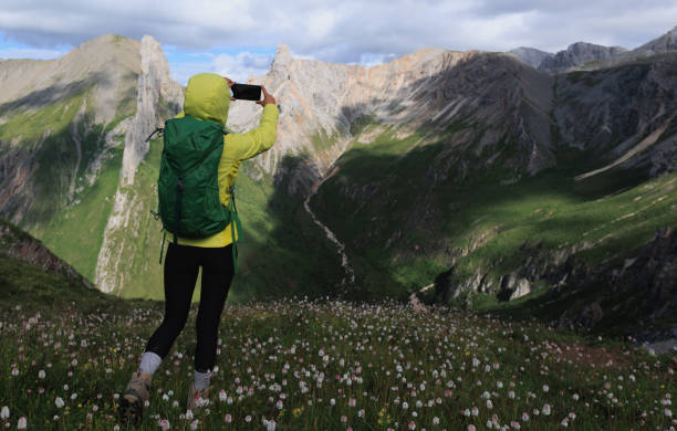 istock Successful woman backpacker using smartphone taking photo hiking on alpine mountain top 2150260682